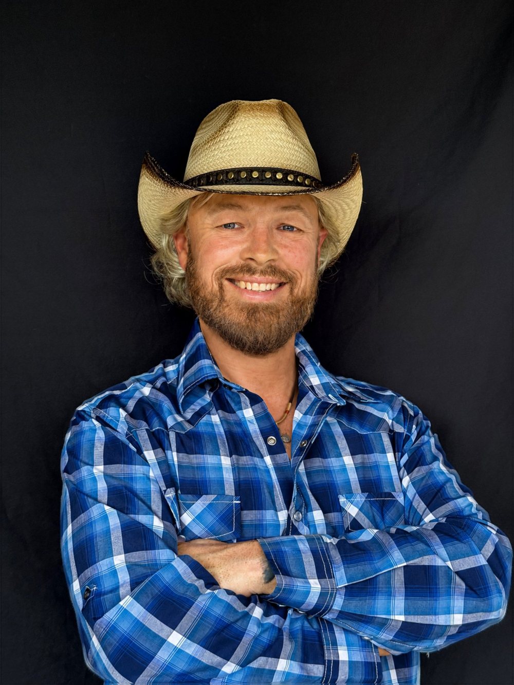 Studio portrait of Joshua Alan in a straw cowboy hat and blue plaid shirt