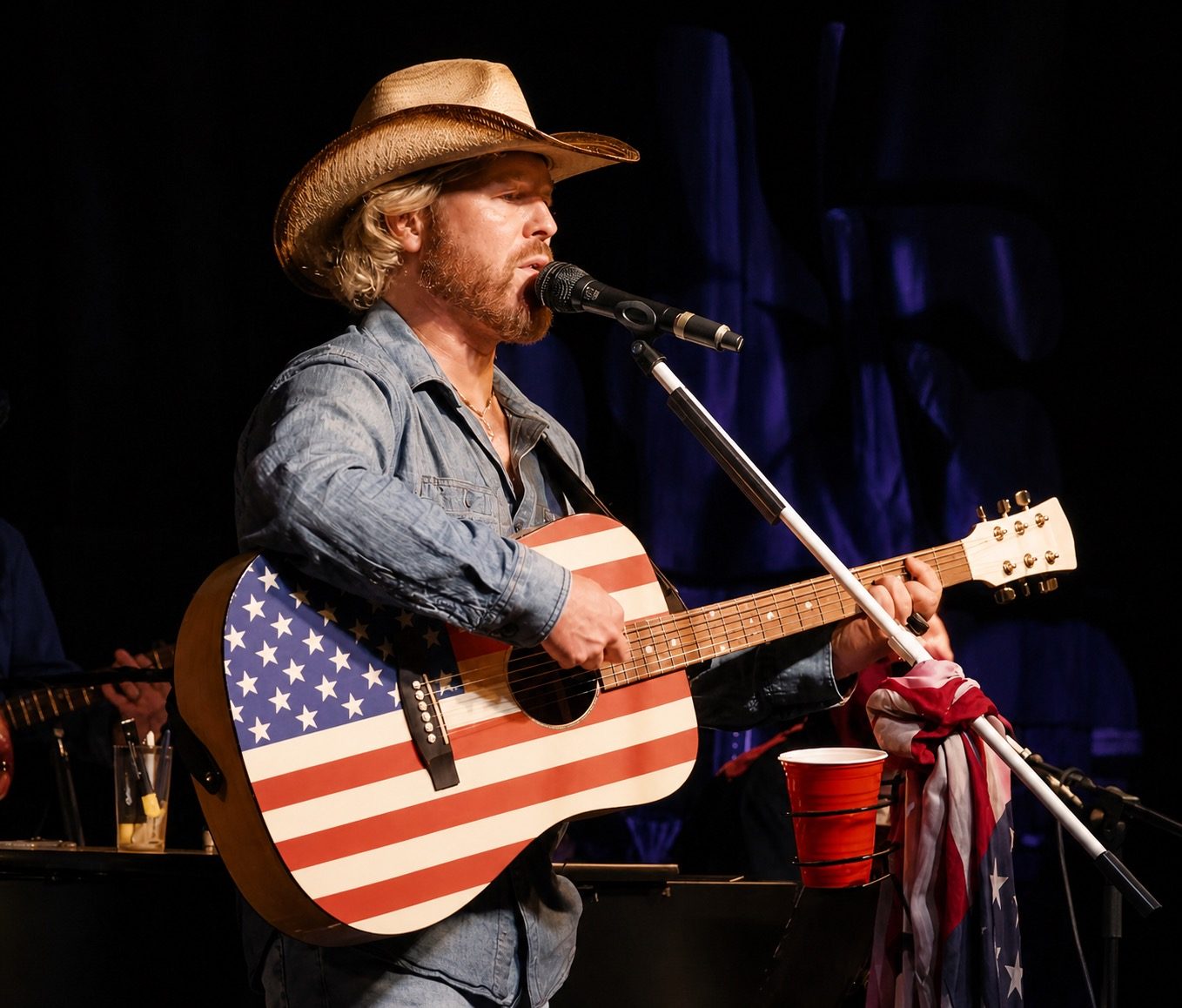 Joshua Rupp singing lead with a stars-and-stripes acoustic guitar